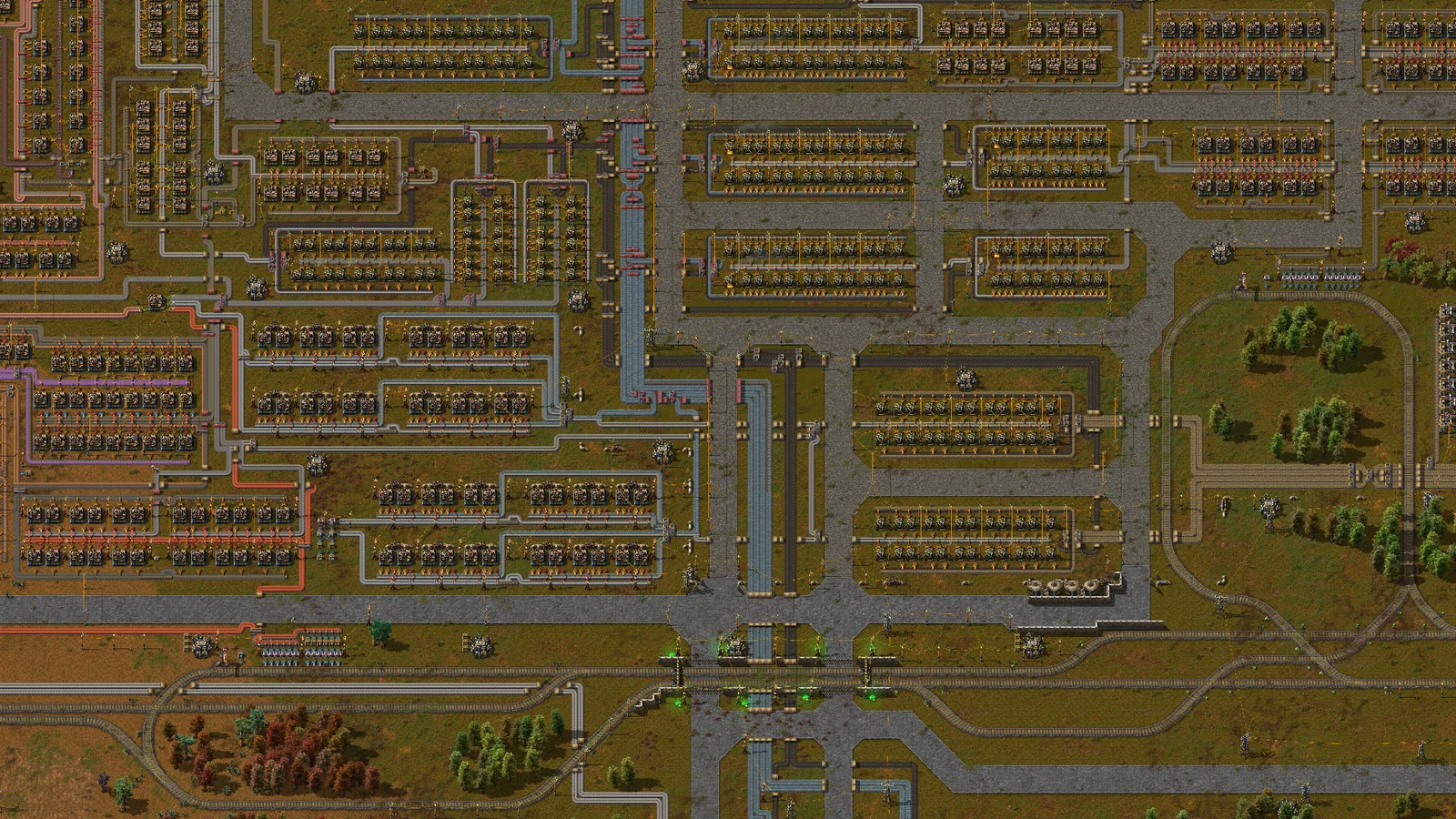 A large Factorio factory with production blocks, conveyor belts, and rail lines