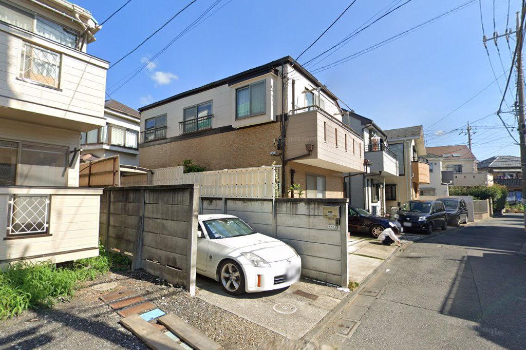 A quiet Tokyo street seen from Google Street View, parked cars and low houses on a narrow road